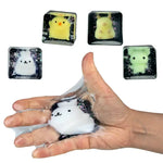 Hand squishing a black glitter cube toy with cute white animal mochi figure inside