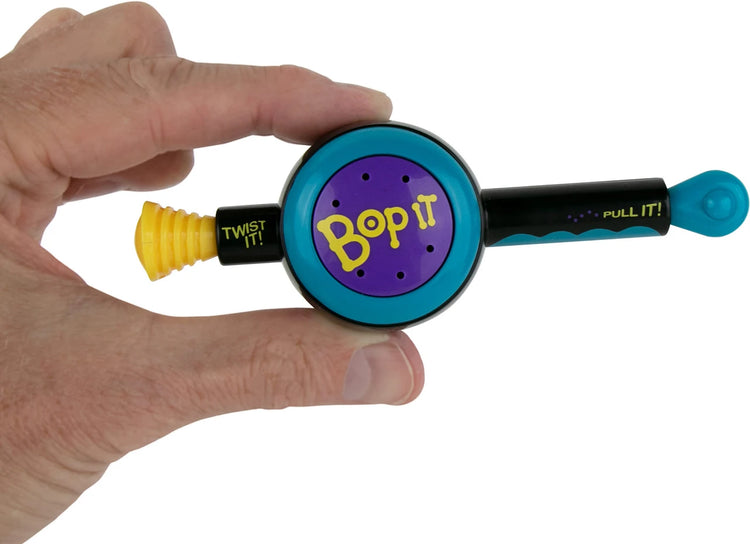 Hand holding miniature Bop It game with twist and pull controls on white background